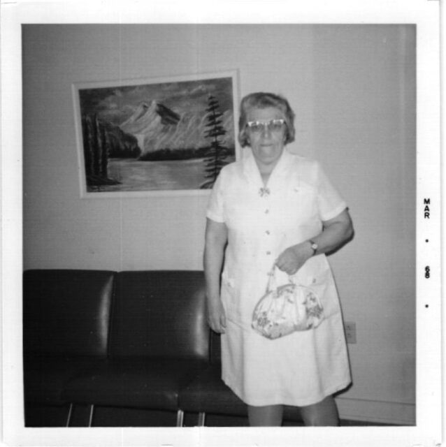 The Little Gray Box, Polly holding purse, standing in lounge, Elk Run Assisted Living in Evergreen, CO